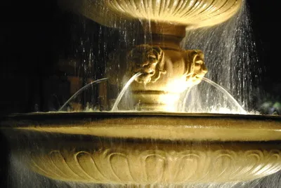 Ornate stone fountain with streams of water lit up at night